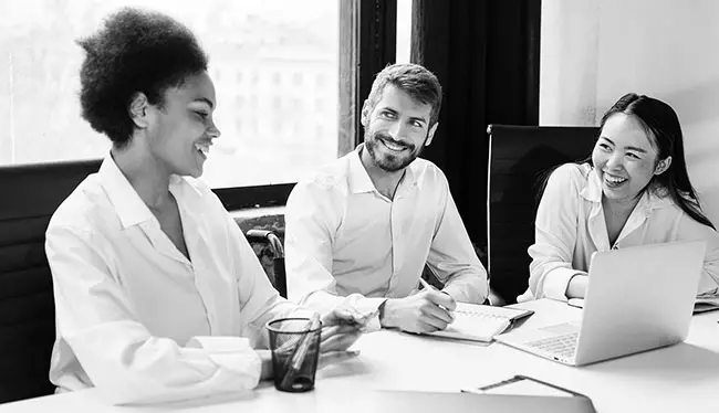 A group of three professionals in an Australian workplace meeting room. The team collaborate on an inclusive recruitment search and selection process.