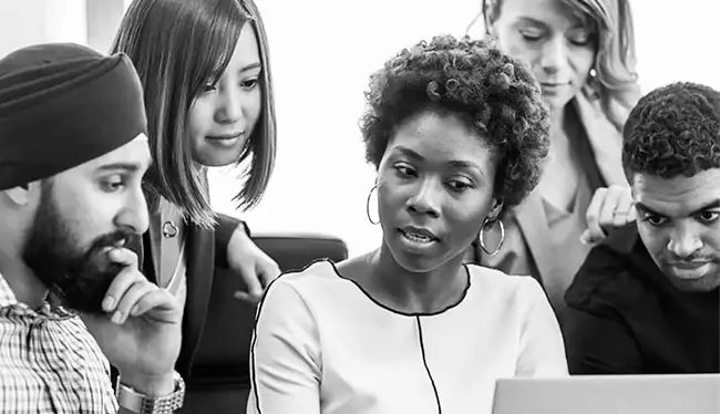 Five professionals from diverse backgrounds collaborate on leadership development planning. They are in an Australian workplace.